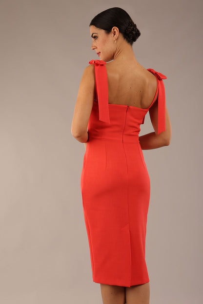 brunette model wearing a diva catwalk Philippa Pencil Wiggle Dress sleeveless style, tie detail on the shoulders knee length and sweetheart neckline in grenadine orange colour front