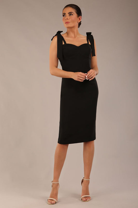 brunette model wearing a diva catwalk Philippa Pencil Wiggle Dress sleeveless style, tie detail on the shoulders knee length and sweetheart neckline in black colour front 