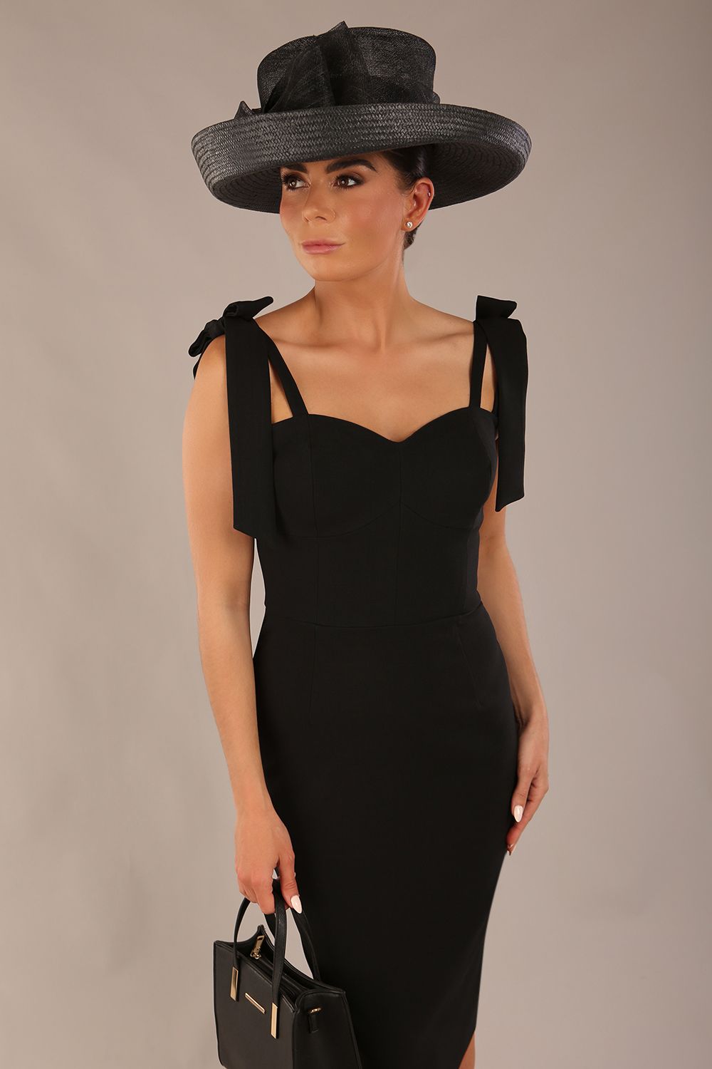 brunette model wearing a diva catwalk Philippa Pencil Wiggle Dress sleeveless style, tie detail on the shoulders knee length and sweetheart neckline in black colour front 