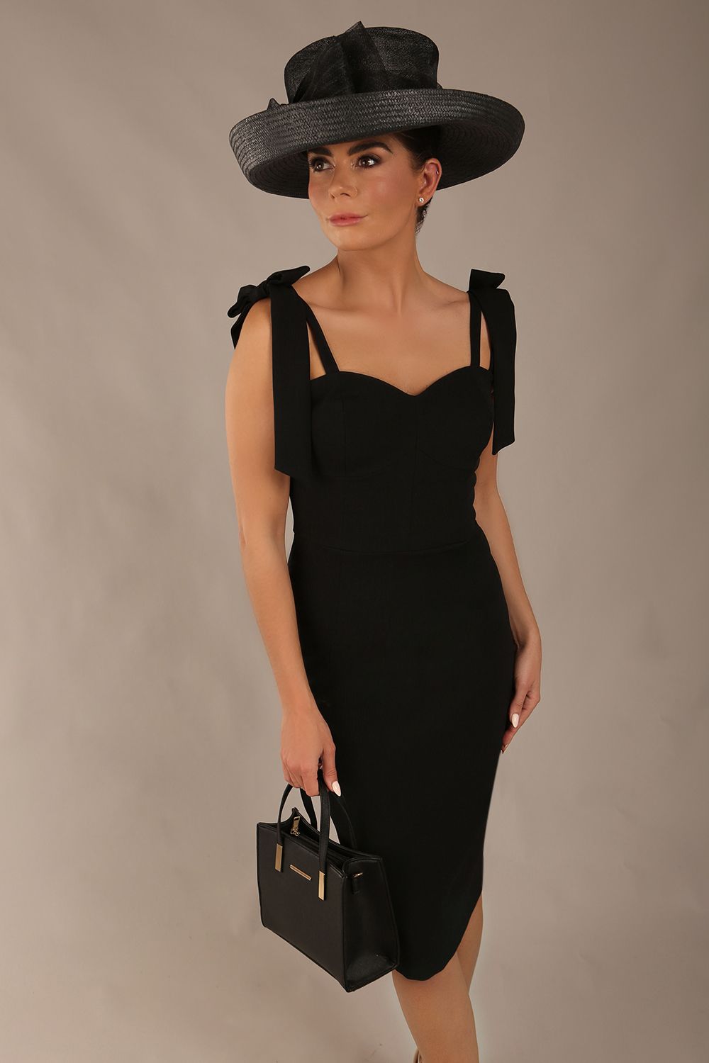 brunette model wearing a diva catwalk Philippa Pencil Wiggle Dress sleeveless style, tie detail on the shoulders knee length and sweetheart neckline in black colour front 