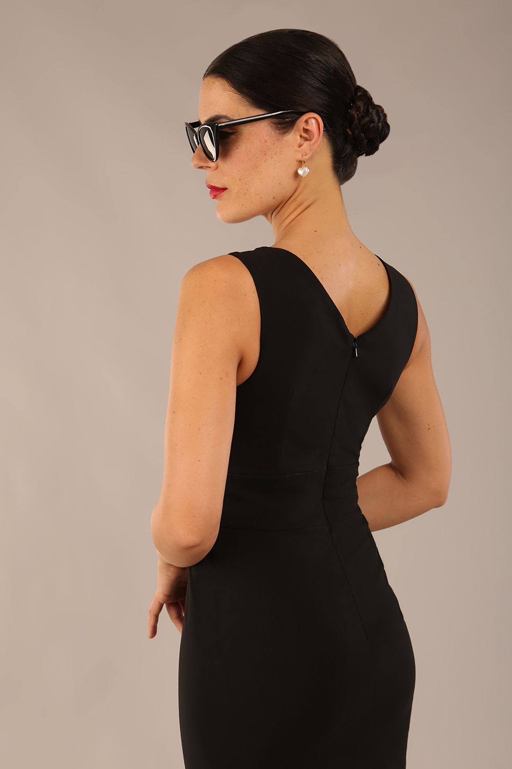 brunette model is wearing a diva catwalk Carrie Pencil Wiggle Dress sleeveless v neck front and back knee length in black colour front image with sunglasses