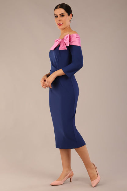 Model is wearing a Rosalind Off Shoulder Bow Detail Pencil Dress 3/4 sleeve in Navy Blue/ Pink contrast front image (Navy Blue / Pink Pearl Contrast)