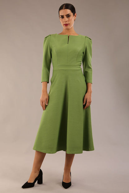 A model wearing a red, 3/4 sleeve A-line dress with pockets, featuring a boat neckline and vent at the centre back (Citrus Green)