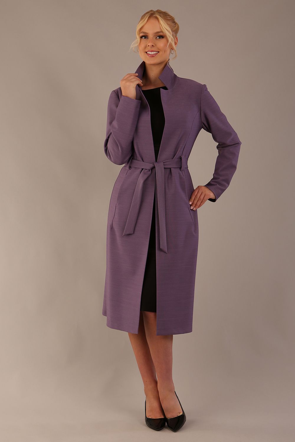 Model wearing a diva catwalk Paloma midi coat worn open over a black dress to show its versatility against a plain background (Dusky Lilac)