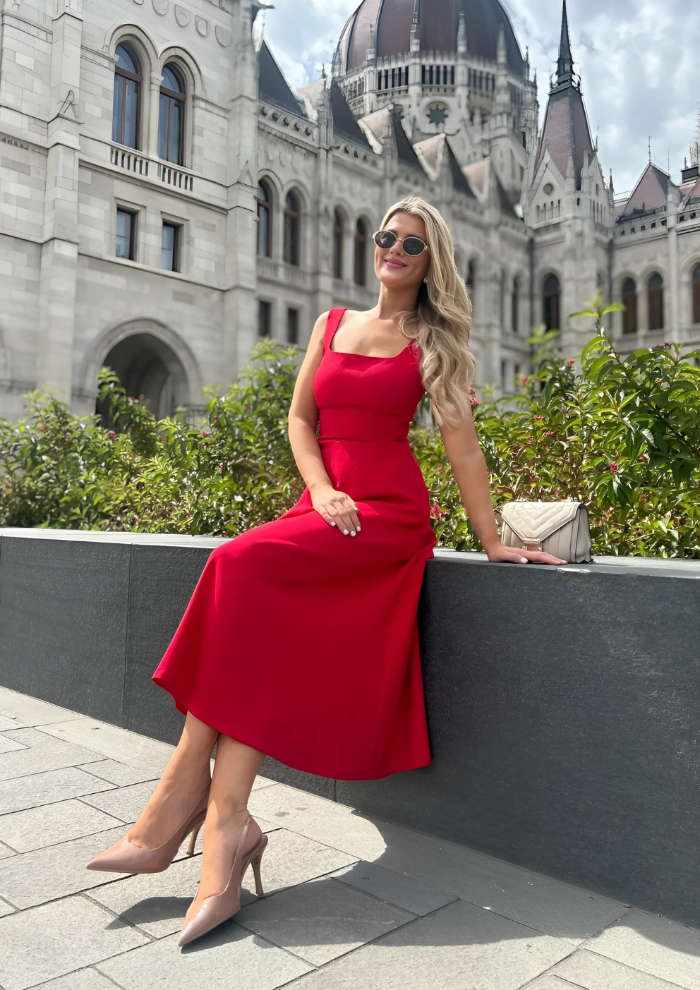woman wearing a diva catwalk Tamsin Square Neckline Swing Dress sleeveless style with a midaxi  length and side pockets in Scarlet Red colour in Budapest (Scarlet Red)