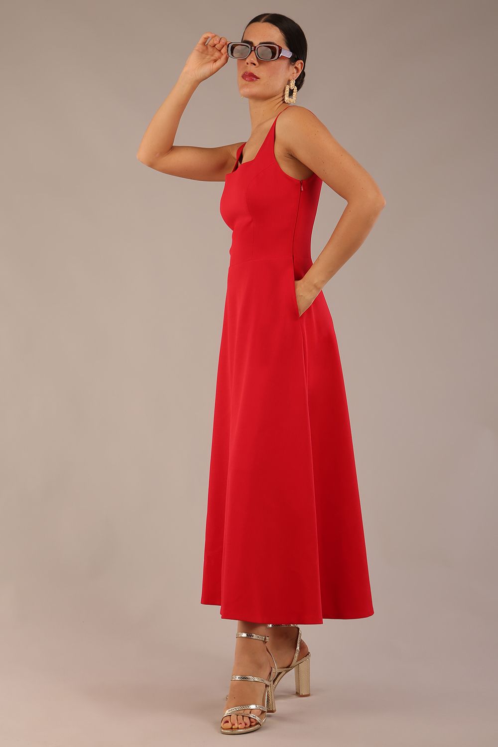 woman wearing a diva catwalk Tamsin Square Neckline Swing Dress sleeveless style with a midaxi  length and side pockets in Scarlet Red colour in Budapest (Scarlet Red)
