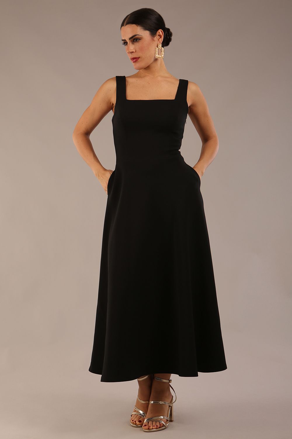 brunette model wearing a diva catwalk Tamsin Square Neckline Swing Dress sleeveless style with a midaxi  length and side pockets in Black colour front (Black)