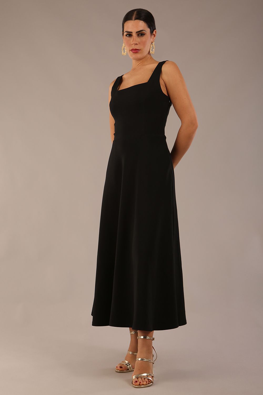 brunette model wearing a diva catwalk Tamsin Square Neckline Swing Dress sleeveless style with a midaxi  length and side pockets in Black colour front (Black)