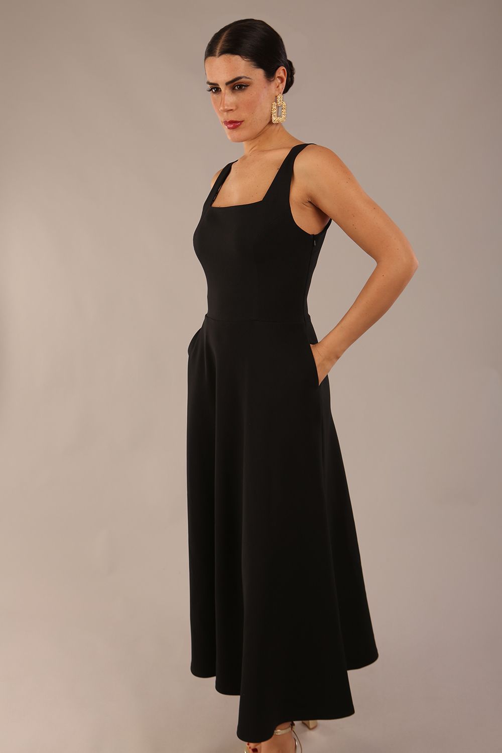 brunette model wearing a diva catwalk Tamsin Square Neckline Swing Dress sleeveless style with a midaxi  length and side pockets in Black colour front (Black)
