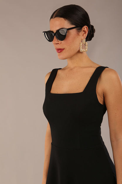 brunette model wearing a diva catwalk Tamsin Square Neckline Swing Dress sleeveless style with a midaxi  length and side pockets in Black colour front (Black)
