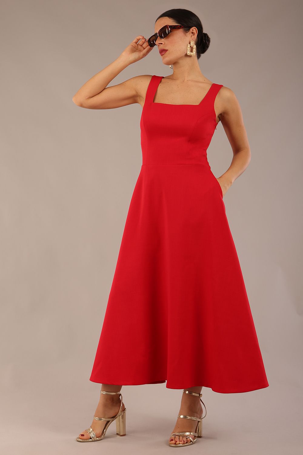 woman wearing a diva catwalk Tamsin Square Neckline Swing Dress sleeveless style with a midaxi  length and side pockets in Scarlet Red colour in Budapest (Scarlet Red)