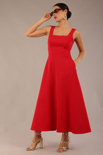 woman wearing a diva catwalk Tamsin Square Neckline Swing Dress sleeveless style with a midaxi  length and side pockets in Scarlet Red colour in Budapest (Scarlet Red)