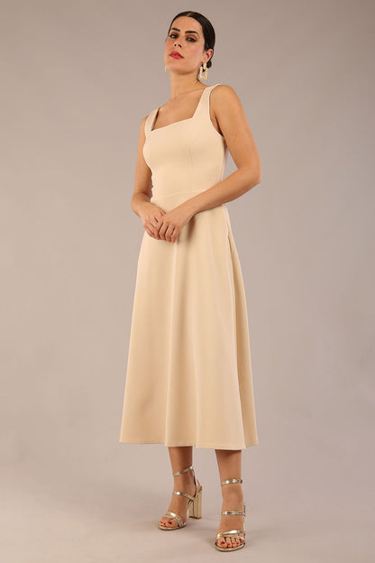 brunette model wearing a diva catwalk Tamsin Square Neckline Swing Dress sleeveless style with a midaxi  length and side pockets in Sandshell Beige colour front (Sandshell Beige)