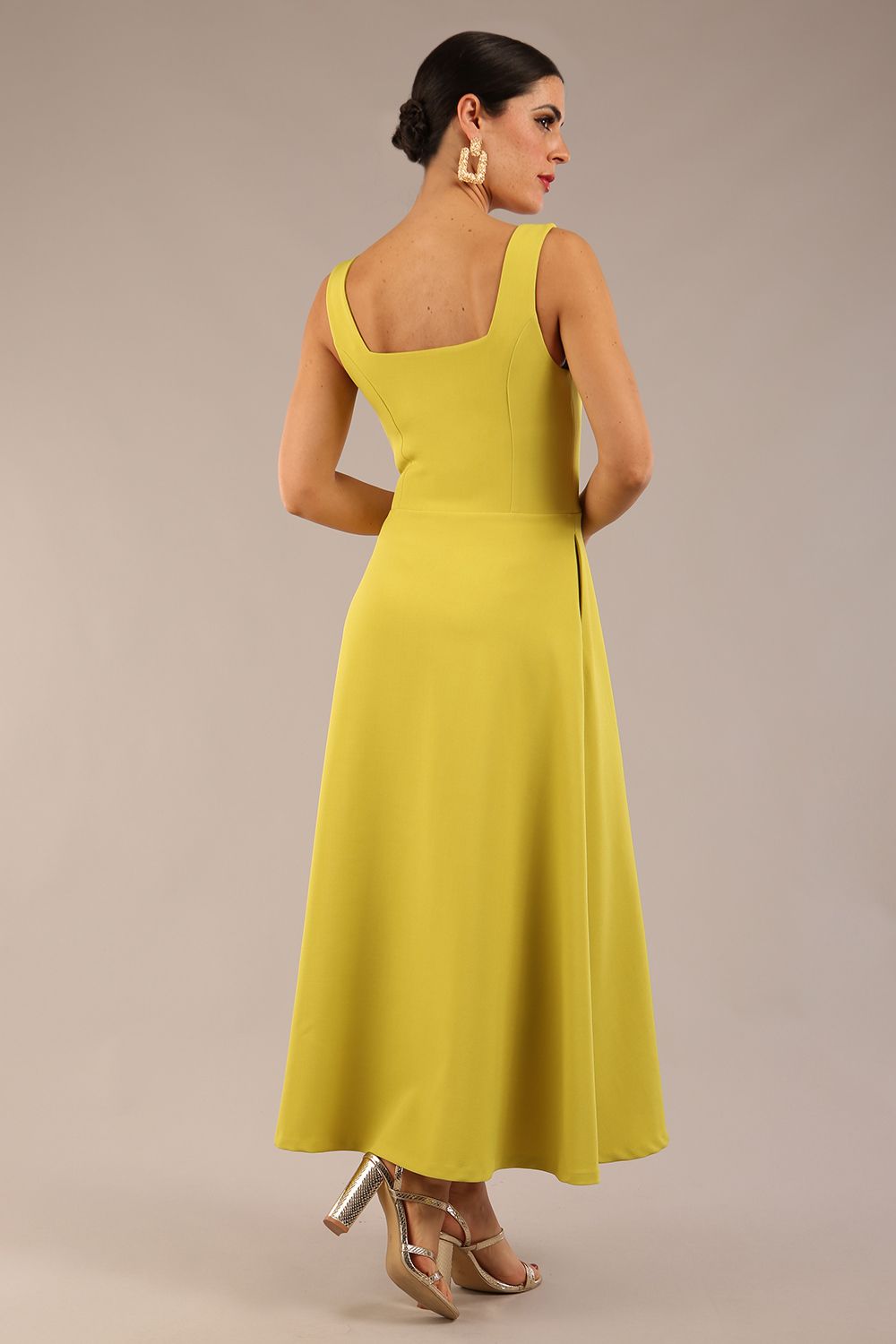 brunette model is wearing a diva catwalk Tamsin Square Neckline Swing Dress sleeveless style with a midaxi  length and side pockets in Citrus green colour front