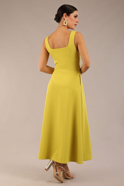 brunette model is wearing a diva catwalk Tamsin Square Neckline Swing Dress sleeveless style with a midaxi  length and side pockets in Citrus green colour front