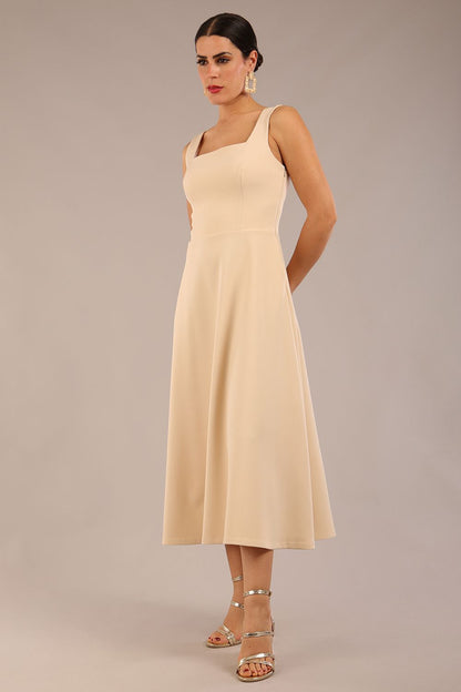 brunette model wearing a diva catwalk Tamsin Square Neckline Swing Dress sleeveless style with a midaxi  length and side pockets in Sandshell Beige colour front (Sandshell Beige)