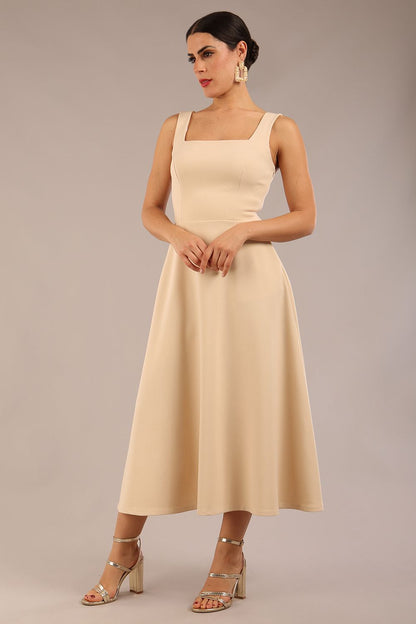 brunette model wearing a diva catwalk Tamsin Square Neckline Swing Dress sleeveless style with a midaxi  length and side pockets in Sandshell Beige colour front (Sandshell Beige)