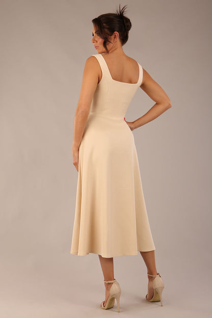 brunette model wearing a diva catwalk Tamsin Square Neckline Swing Dress sleeveless style with a midaxi  length and side pockets in Sandshell Beige colour front (Sandshell Beige)