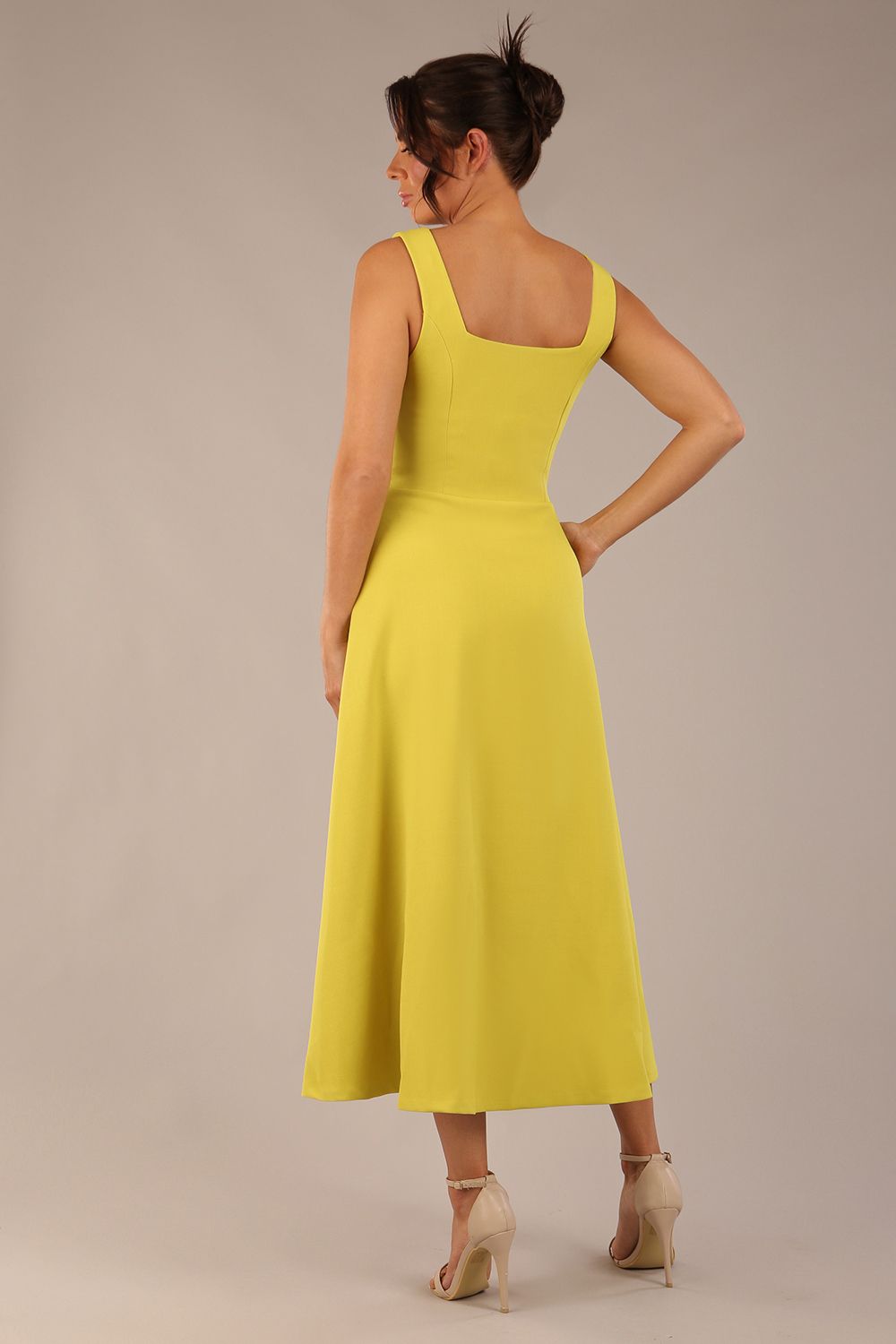 brunette model is wearing a diva catwalk Tamsin Square Neckline Swing Dress sleeveless style with a midaxi  length and side pockets in Citrus green colour front