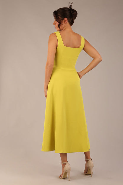 brunette model is wearing a diva catwalk Tamsin Square Neckline Swing Dress sleeveless style with a midaxi  length and side pockets in Citrus green colour front