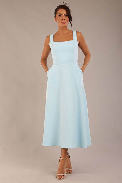 brunette model is wearing a diva catwalk Tamsin Square Neckline Swing Dress sleeveless style with a midaxi  length and side pockets in Sky blue colour front