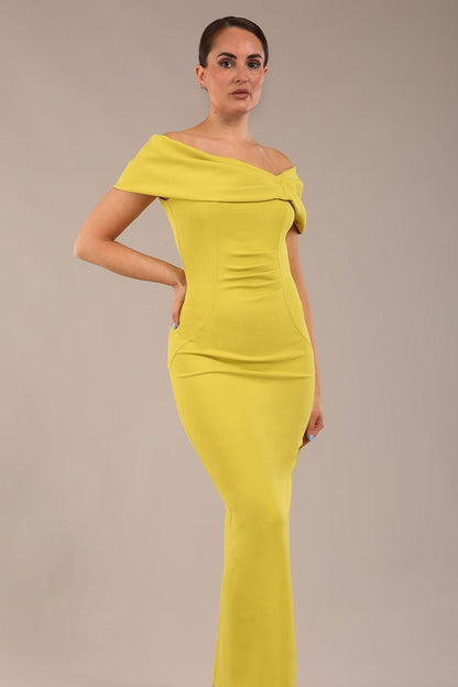 brunette model is wearing a diva catwalk Mariposa Longer Length Dress off the shoulder bardot neckline and midaxi length in citrus green colour front image