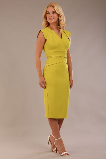 model wearing a diva catwalk Caprice Cap Sleeved Pencil Dress cap sleeve v neckline knee length with pleating details in citrus green colour front side