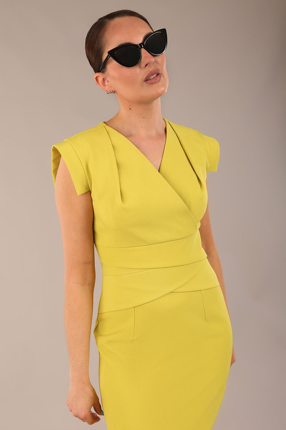 model wearing a diva catwalk Caprice Cap Sleeved Pencil Dress cap sleeve v neckline knee length with pleating details in citrus green colour front