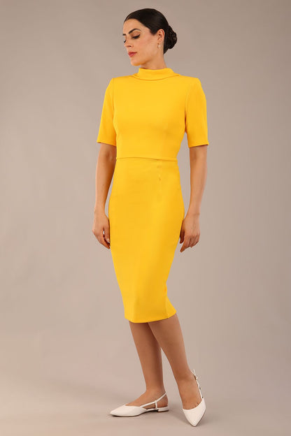 brunette model is wearing a diva catwalk Highmoor Short Sleeved Pencil Dress high neckline and shoulders pad in sunshine yellow colour back image close up