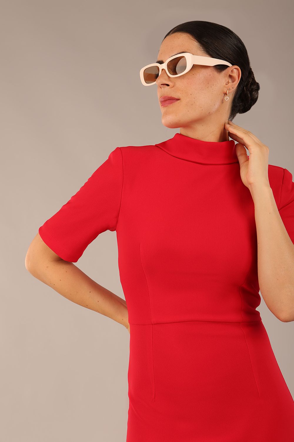 brunette model is wearing a diva catwalk Highmoor Short Sleeved Pencil Dress high neckline and shoulders pad in true red colour front image