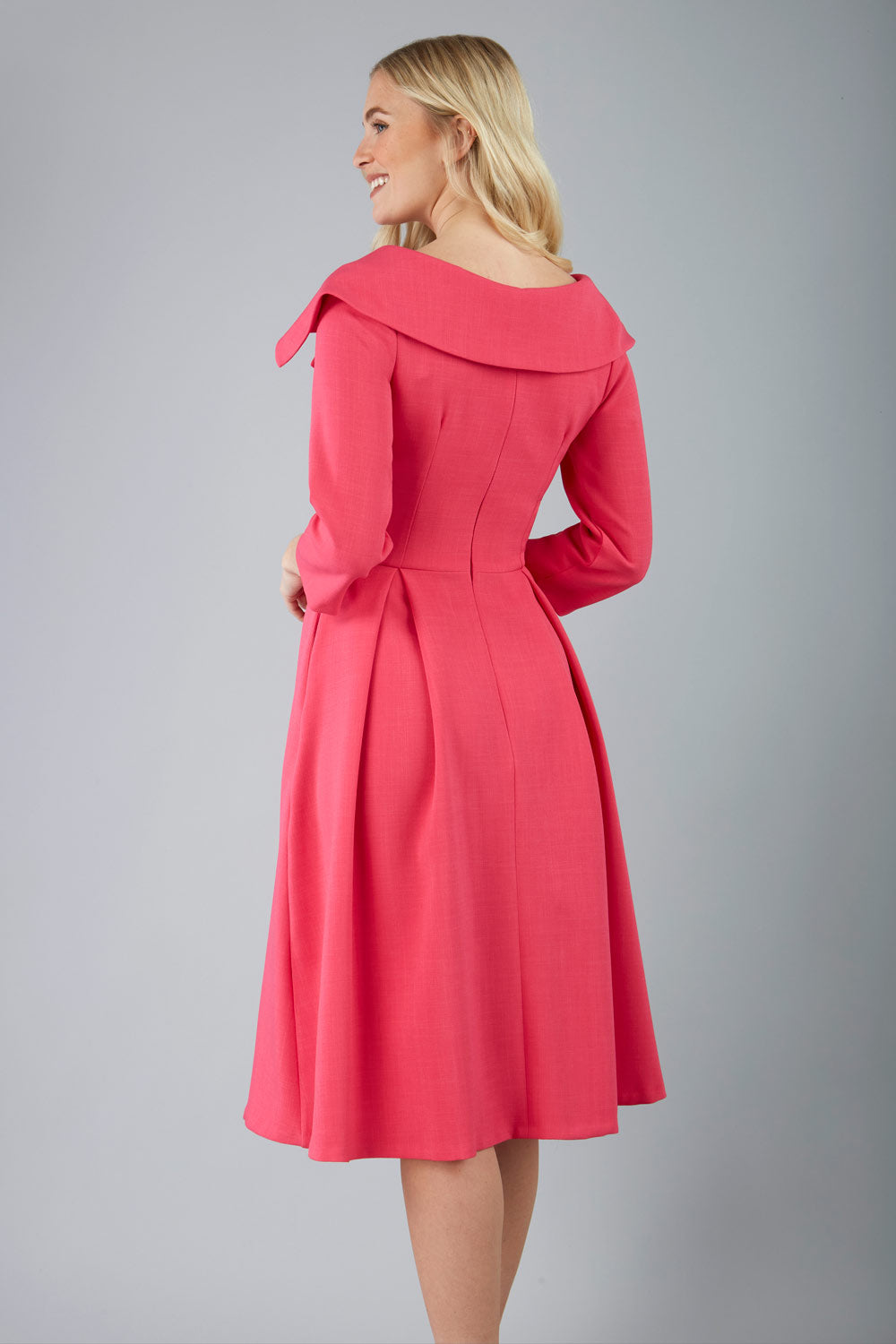 model is wearing diva catwalk gatsby swing dress with pocket detail and wide v-neck collar and buttons down the front panel in hibiscus pink front