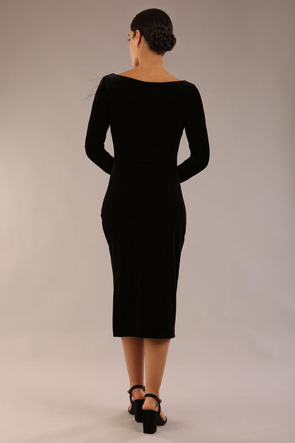 model is wearing a diva catwalk Renoir Long Sleeve Velvet Dress long sleeves midi length with side vent and asymmetric neckline and pleating details in black velvet