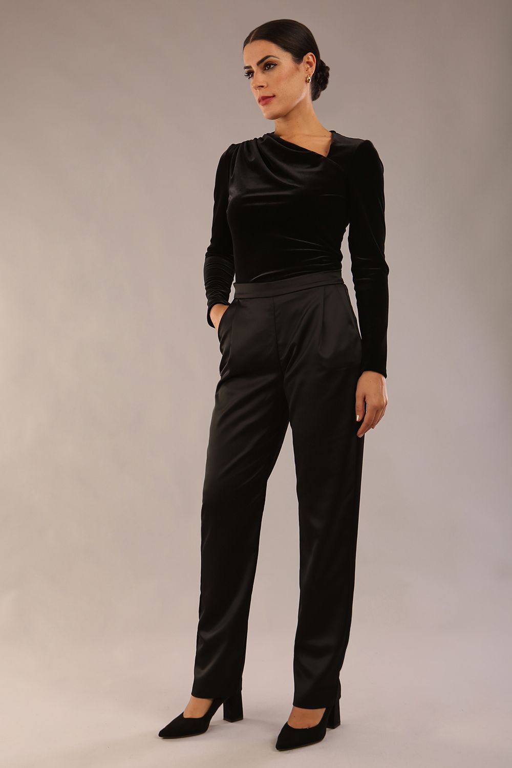 model is wearing a diva catwalk Rhea Satin Stretch Trousers with side pockets and concealed side zip and long leg in black satin