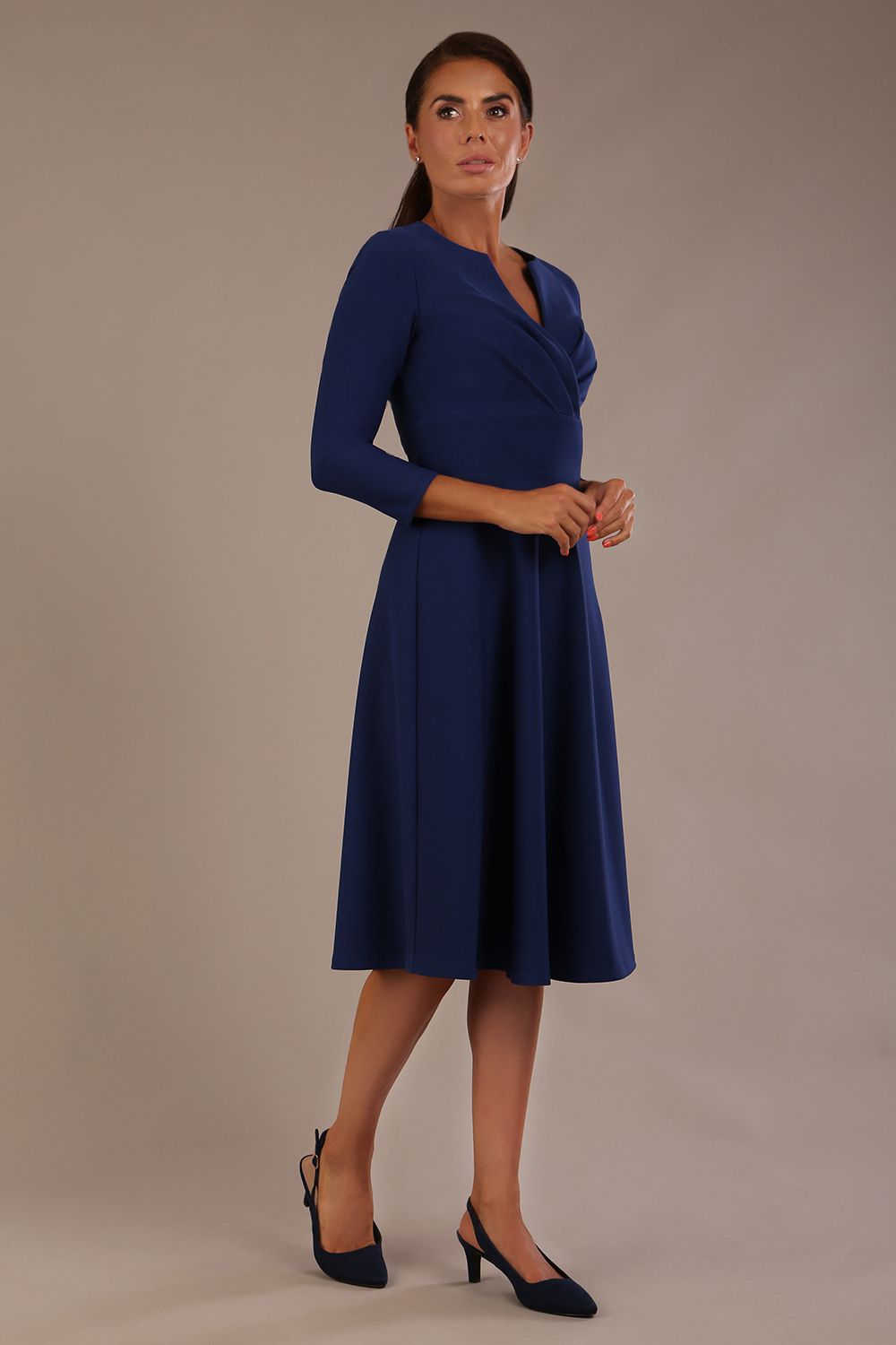 brunette model is wearing a diva catwalk Haddington sleeved A-line Dress knee length round neckline with crossover v-slit detail in navy blue colour front image