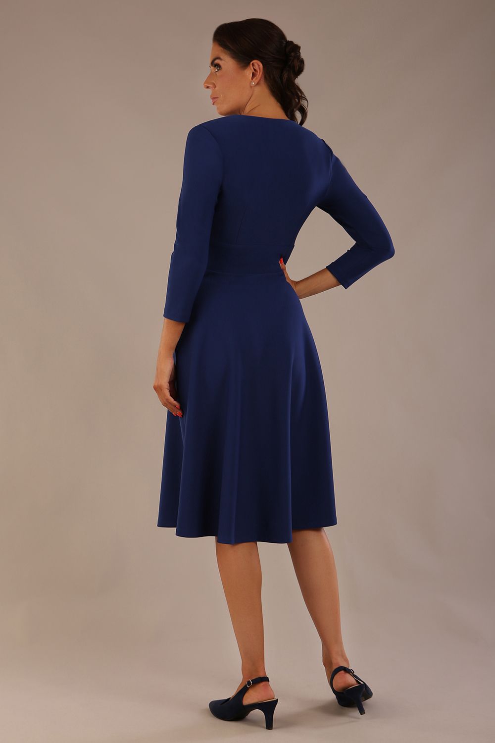 brunette model is wearing a diva catwalk Haddington sleeved A-line Dress knee length round neckline with crossover v-slit detail in navy blue colour front image