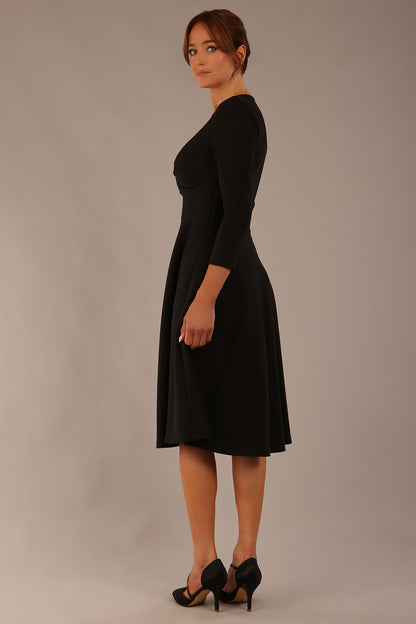 brunette model is wearing a diva catwalk Haddington sleeved A-line Dress knee length round neckline with crossover v-slit detail in black colour front image 