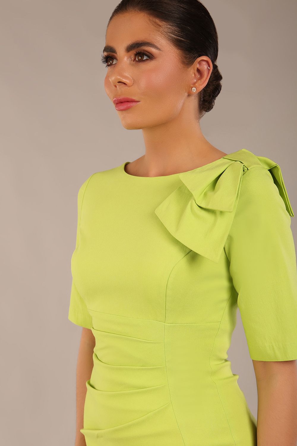 brunette model is wearing a diva catwalk Reverie Short Sleeve Stretch Pencil Dress with Bow Detail in lime green colour front image