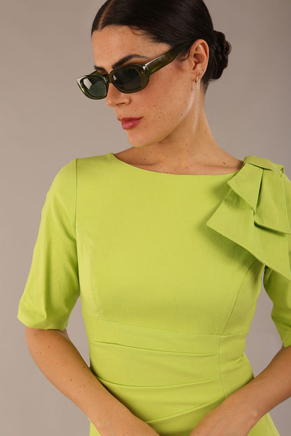 brunette model is wearing a diva catwalk Reverie Short Sleeve Stretch Pencil Dress with Bow Detail in lime green colour front image