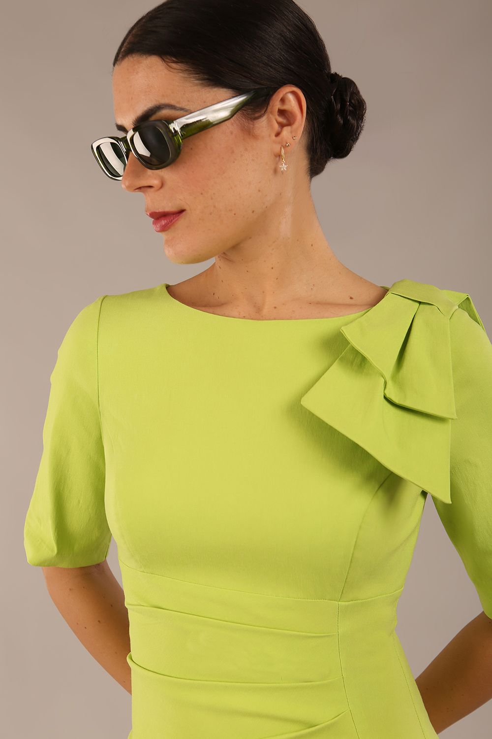 brunette model is wearing a diva catwalk Reverie Short Sleeve Stretch Pencil Dress with Bow Detail in lime green colour front image