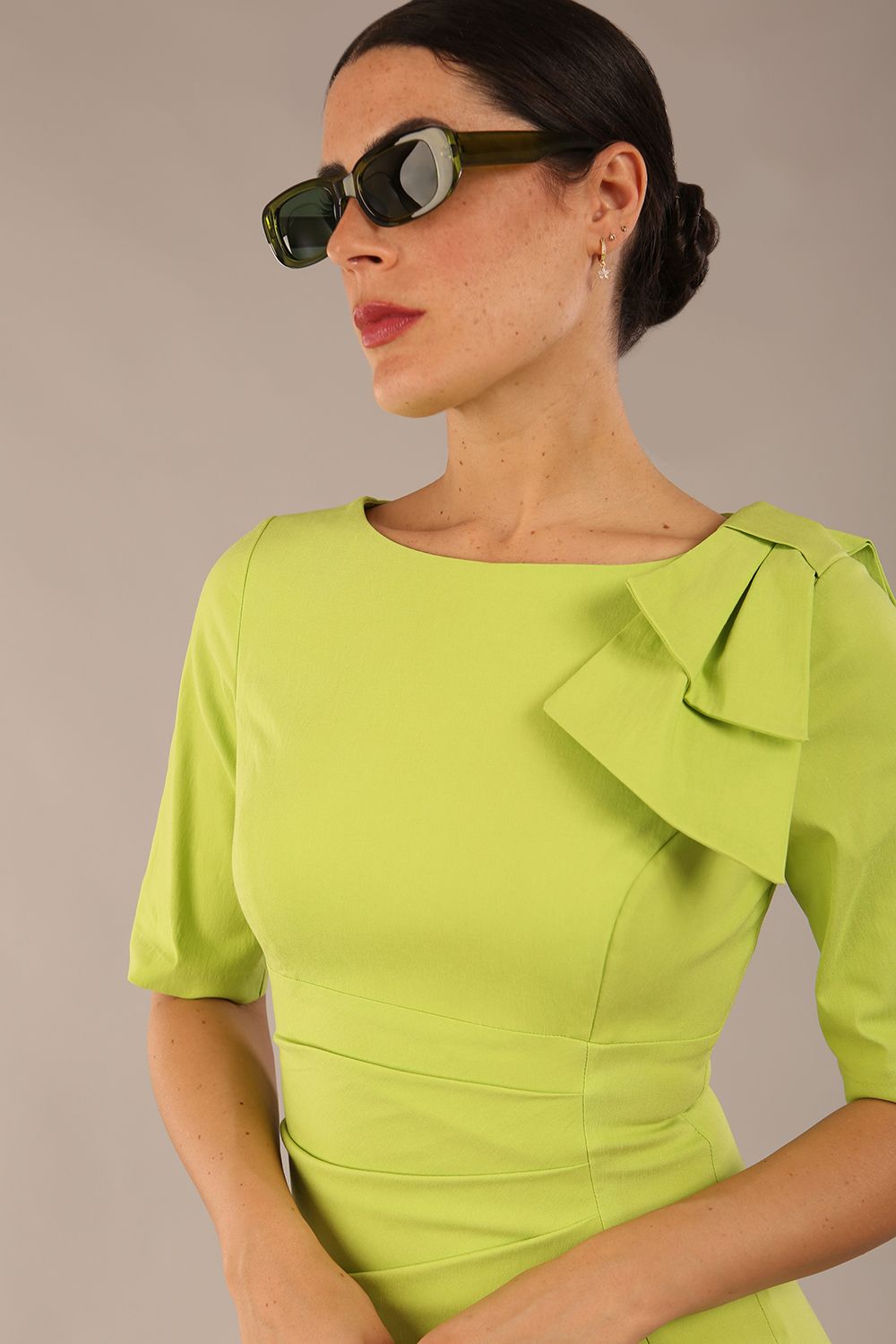 brunette model is wearing a diva catwalk Reverie Short Sleeve Stretch Pencil Dress with Bow Detail in lime green colour front image