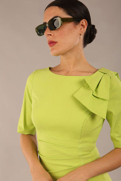 brunette model is wearing a diva catwalk Reverie Short Sleeve Stretch Pencil Dress with Bow Detail in lime green colour front image