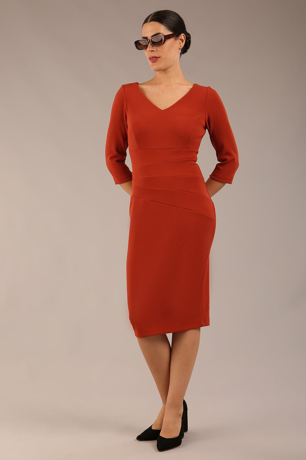 blonde model is wearing a  diva catwalk Tara V-neckline Sleeved Pencil Dress knee length in terracotta brown colour front image (Terracotta)