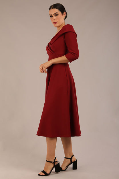 brunette model is wearing a diva catwalk Fabienne sleeved A-line Dress with pockets v neckline knee length wide waistband fold over v neckline in burgundy colour front image (Rio Red)