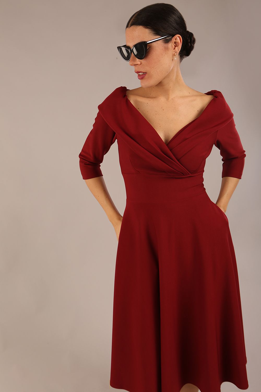 brunette model is wearing a diva catwalk Fabienne sleeved A-line Dress with pockets v neckline knee length wide waistband fold over v neckline in burgundy colour front image (Rio Red)