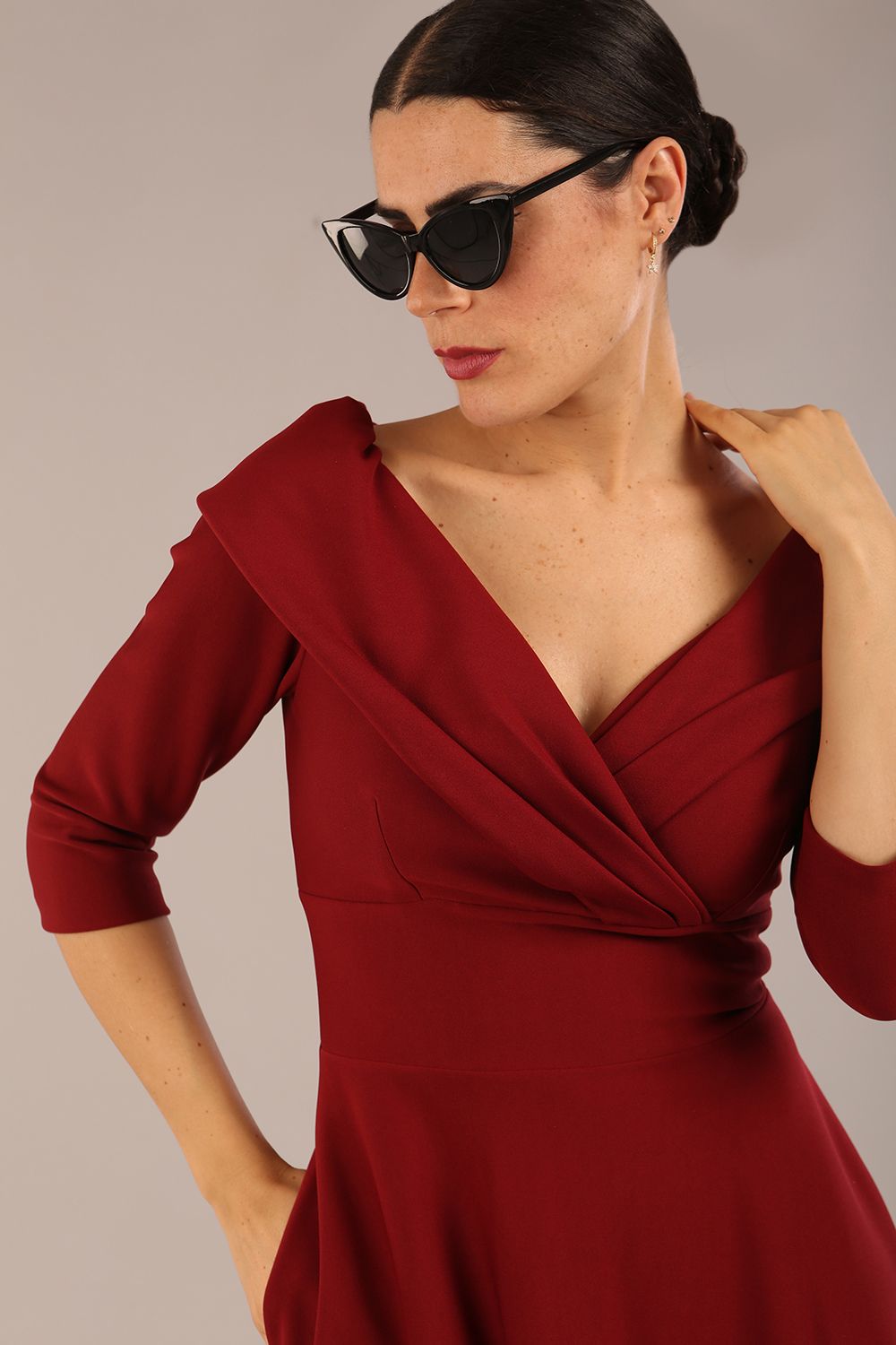 brunette model is wearing a diva catwalk Fabienne sleeved A-line Dress with pockets v neckline knee length wide waistband fold over v neckline in burgundy colour front image (Rio Red)