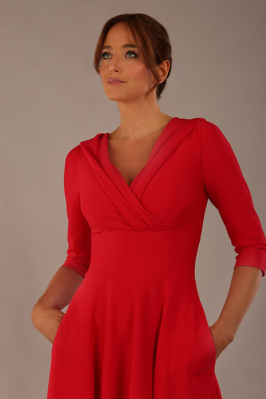 brunette model is wearing a diva catwalk Fabienne sleeved A-line Dress with pockets v neckline knee length wide waistband fold over v neckline in electric red colour front image (Electric Red)