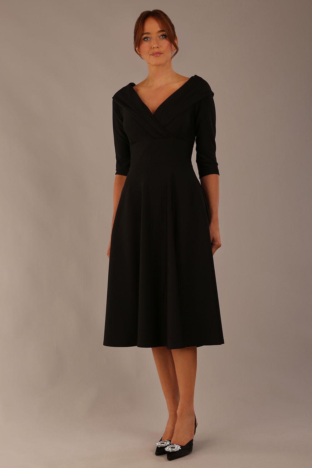brunette model is wearing a diva catwalk Fabienne sleeved A-line Dress with pockets v neckline knee length wide waistband fold over v neckline in black colour front image (Black)