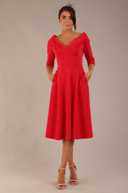 brunette model is wearing a diva catwalk Fabienne sleeved A-line Dress with pockets v neckline knee length wide waistband fold over v neckline in electric red colour front image (Electric Red)