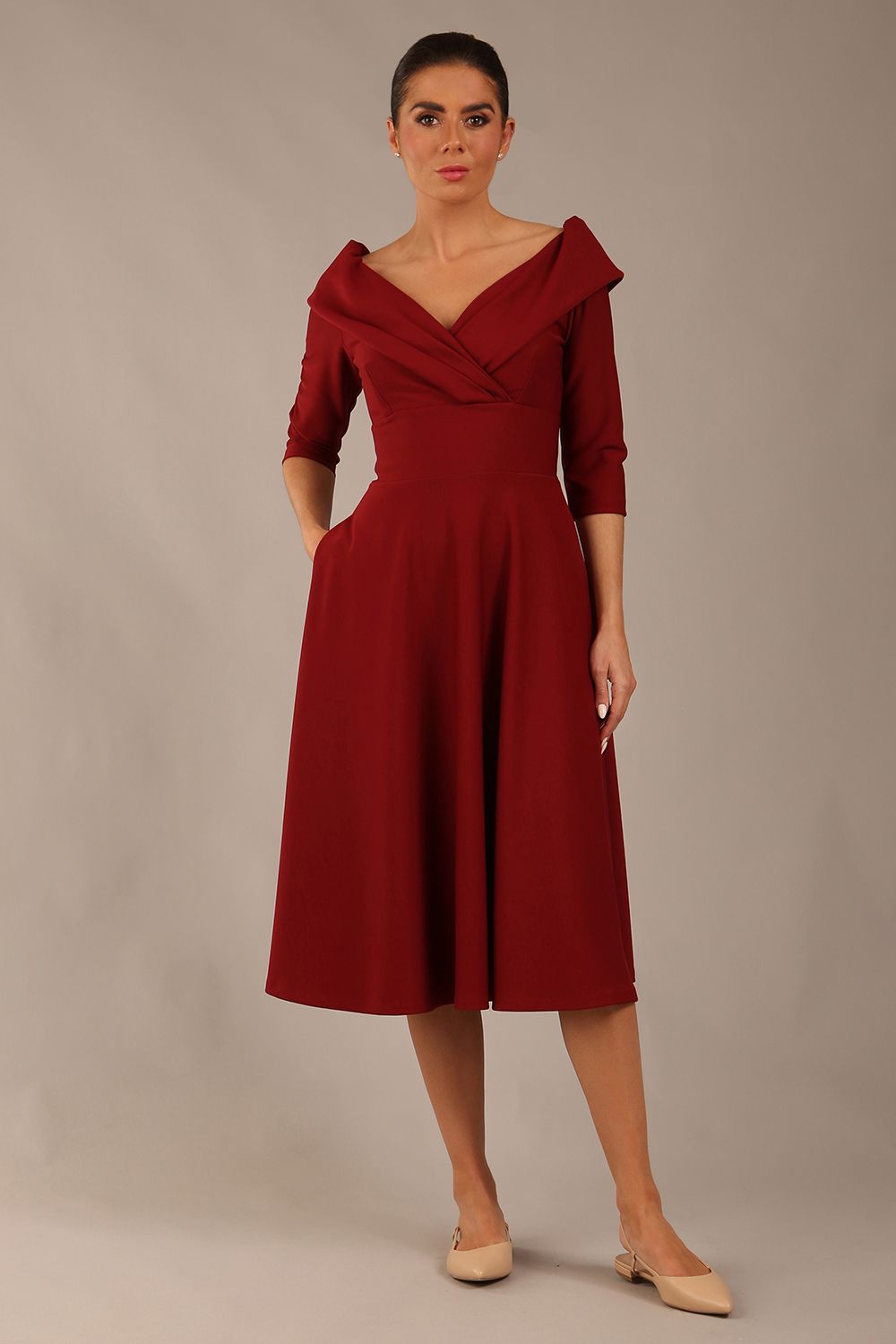 brunette model is wearing a diva catwalk Fabienne sleeved A-line Dress with pockets v neckline knee length wide waistband fold over v neckline in burgundy colour front image (Rio Red)