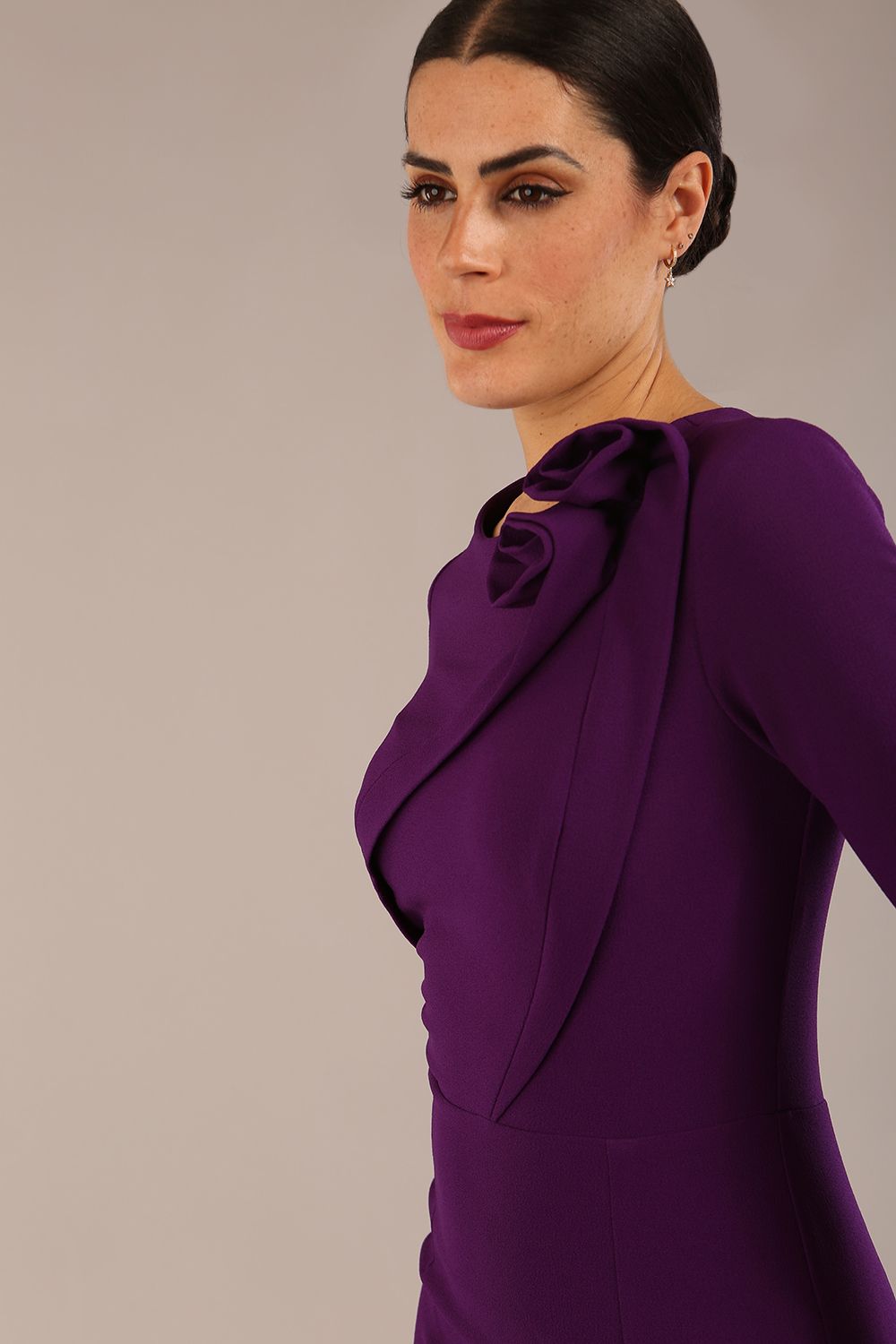 brunette model is wearing a diva catwalk Mirabelle ¾ Sleeves & Floral Shoulder Detail Pencil Dress with diagonal pleating across the front knee length in purple colour front image